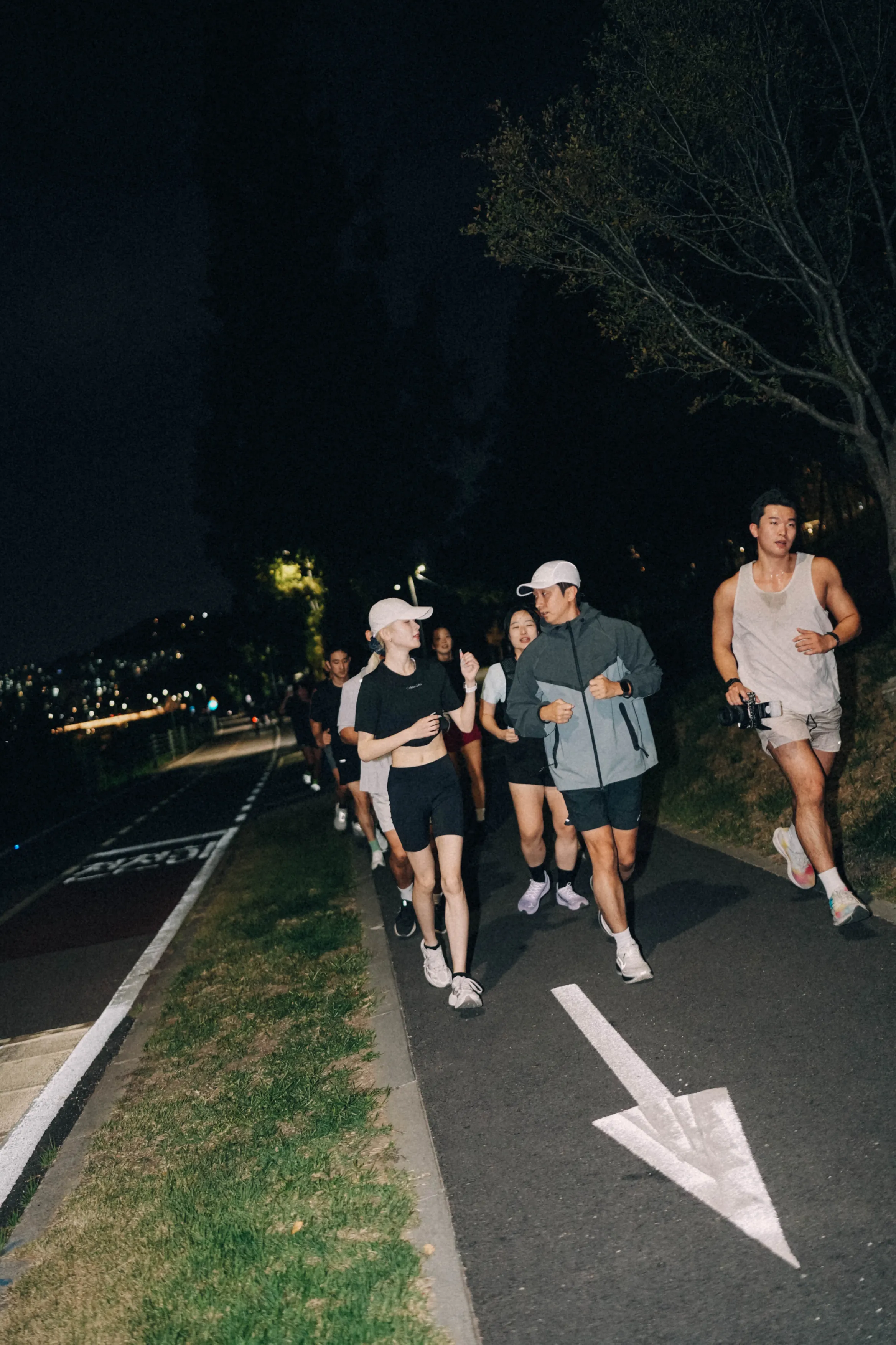 A group of runners on a riverside path at night